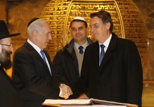 Brazilian President Jair Bolsonaro (R) and Israeli Prime Minister Benjamin Netanyahu (2nd-L) shake hands near the Rabbi of the Western Wall Shmuel Rabinovitch (L) and Bolsonaro's son Flavio (C) during a visit to a synagogue inside the Western Wall Tunnels in Jerusalem's Old City on April 1, 2019