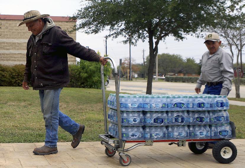 Leeroy Luna, from Calallen Independent School District, moves cases of water to Magee Elementary School, Thursday morning, Dec. 15, 2016, in Corpus Christi, Texas. The city is warning its 320,000 residents not to use tap water because it might be contaminated with petroleum-based chemicals, prompting a rush on bottled water and the closure of local schools. (Gabe Hernandez/Corpus Christi Caller-Times via AP)