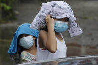 Young girls wearing masks to prevent the spread of the coronavirus place clothes to shelter them from rain due to Typhoon Molave in Pampanga province, northern Philippines on Monday, Oct. 26, 2020. A fast moving typhoon has forced thousands of villagers to flee to safety in provinces. (AP Photo/Aaron Favila)