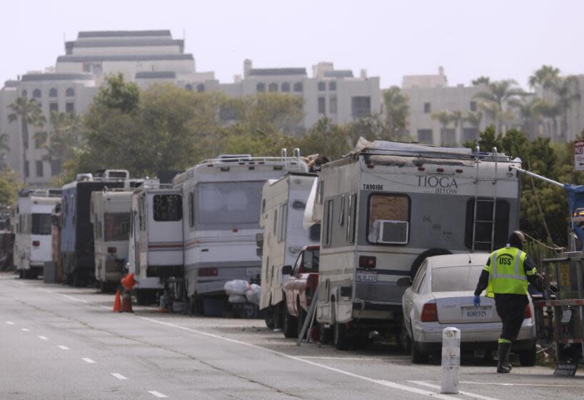 MARINA DEL REY, CA - MAY 24, 2022 - - A worker prepares to clean a portable restroom that the homeless use near a line of campers that make up the Balloon Creek homeless encampment along Jefferson Boulevard in Marina Del Rey on May 24, 2023. A new LAPD report links RV encampments with increased crime in the surrounding areas and mentions the Ballona Creek encampment as problematic. (Genaro Molina / Los Angeles Times)