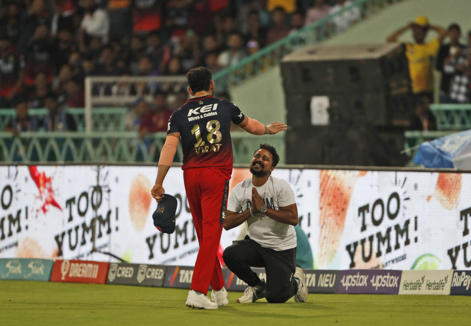 A fan jumps into the field to greets Royal Challengers Bangalore's Virat Kohli during the Indian Premier League (IPL) match between Lucknow Super Giants and Royal Challenger Bangalore in Lucknow, India, Monday, May 1, 2023. (AP Photo/Surjeet Yadav)