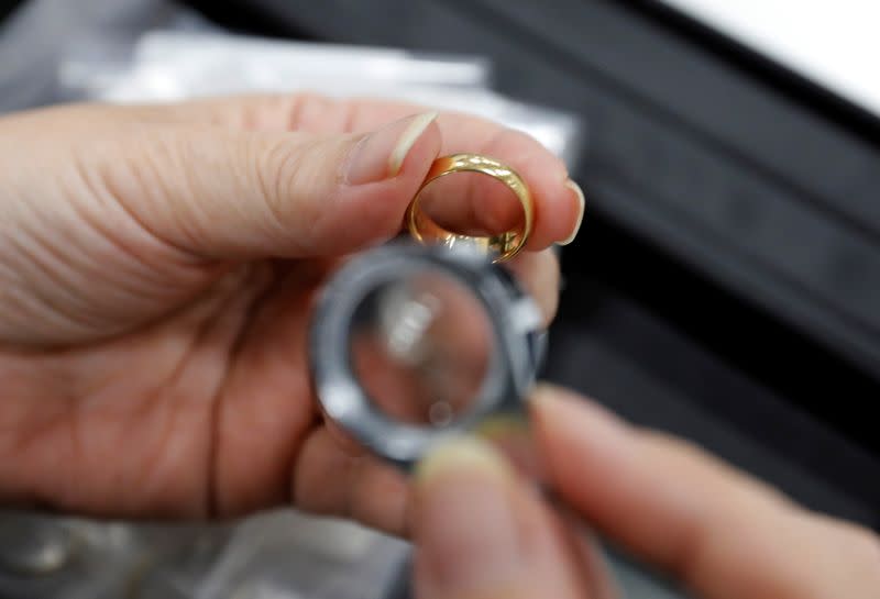 Buysell Technologies worker assesses gold ring in Funabashi