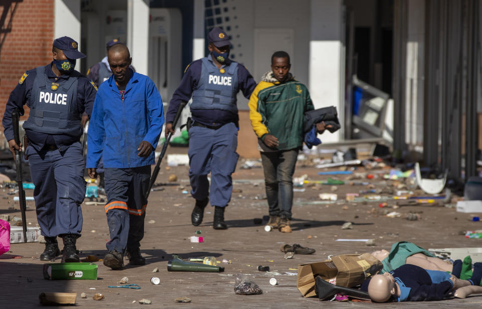 Police officers arrest people after looting groceries at Letsoho Shopping Centre in Katlehong, east of Johannesburg, South Africa, Monday, July 12, 2021. Police say six people are dead and more than 200 have been arrested amid escalating violence during rioting that broke out following the imprisonment of South Africa's former President Jacob Zuma. (AP Photo/Themba Hadebe)