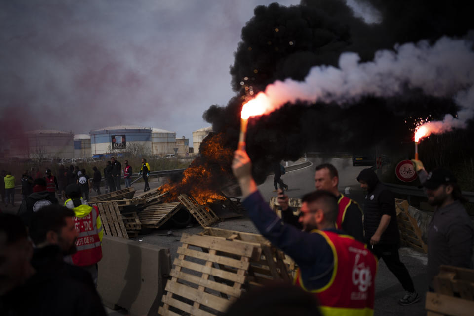 Oil workers block the access to an oil depot in Fos-sur-Mer, southern France, Tuesday, March 21, 2023. The bill pushed through by President Emmanuel Macron without lawmakers' approval still faces a review by the Constitutional Council before it can be signed into law. Meanwhile, oil shipments in the country were disrupted amid strikes at several refineries in western and southern France. (AP Photo/Daniel Cole)