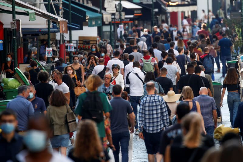 People wearing protective face masks walk in a busy street in Paris