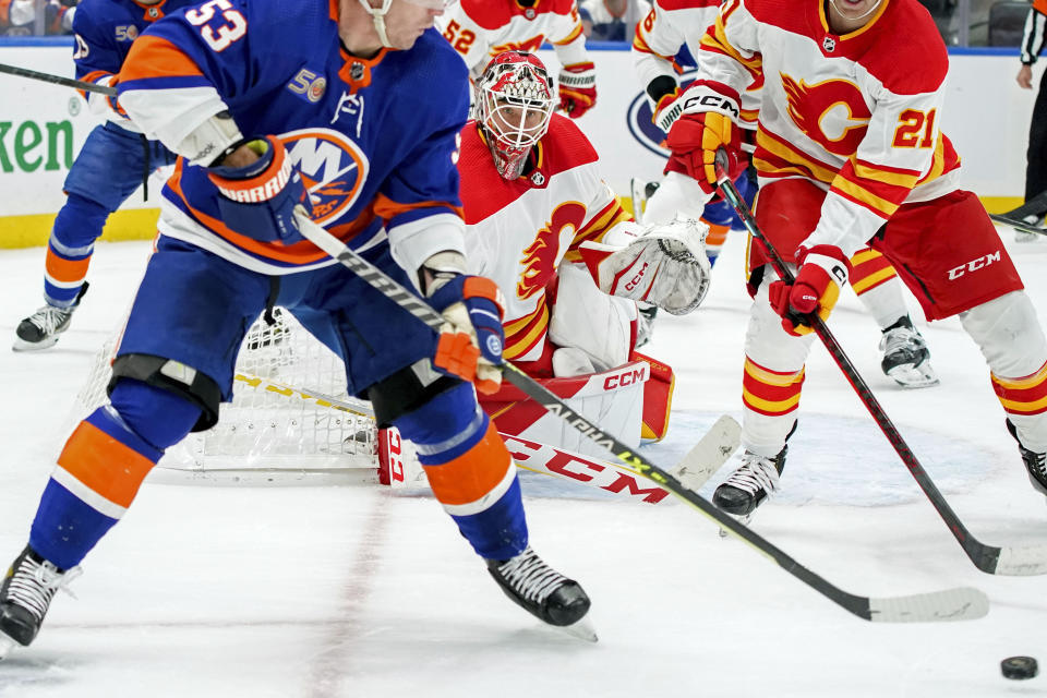 Calgary Flames goaltender Jacob Markstrom (25) watches center Kevin Rooney (21) and New York Islanders center Casey Cizikas (53) fight for the puck during the second period of an NHL hockey game, Monday, Nov. 7, 2022, in Elmont, N.Y. (AP Photo/Julia Nikhinson)