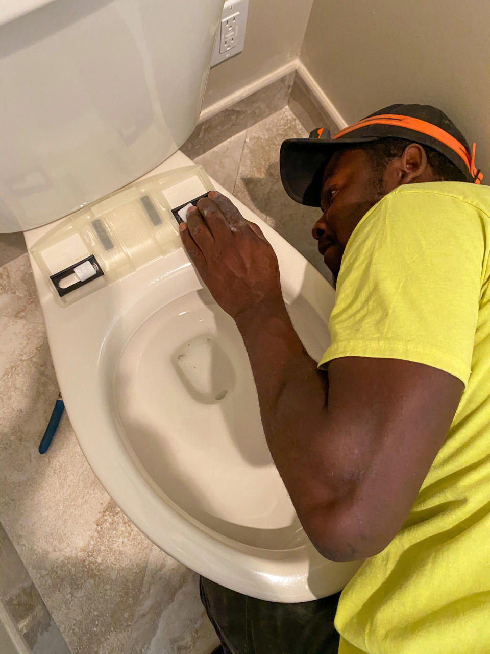 man installing a bidet attachment on a toilet