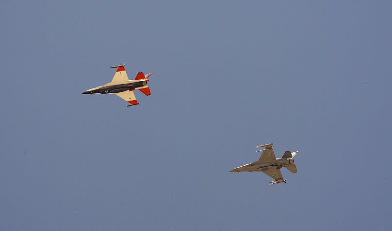 Un avión de combate F-16 de la Fuerza Aérea con IA, a la izquierda, vuela junto a un F-16 adversario, mientras ambos aviones vuelan a 304 metros de distancia entre ellos.