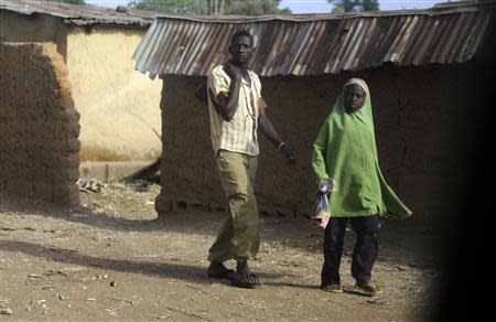 A man and a girl walk on a street in Bakin Kogi, Zango kataf, Kaduna State, March 22, 2014. Picture taken March 22, 2014. REUTERS/Afolabi Sotunde