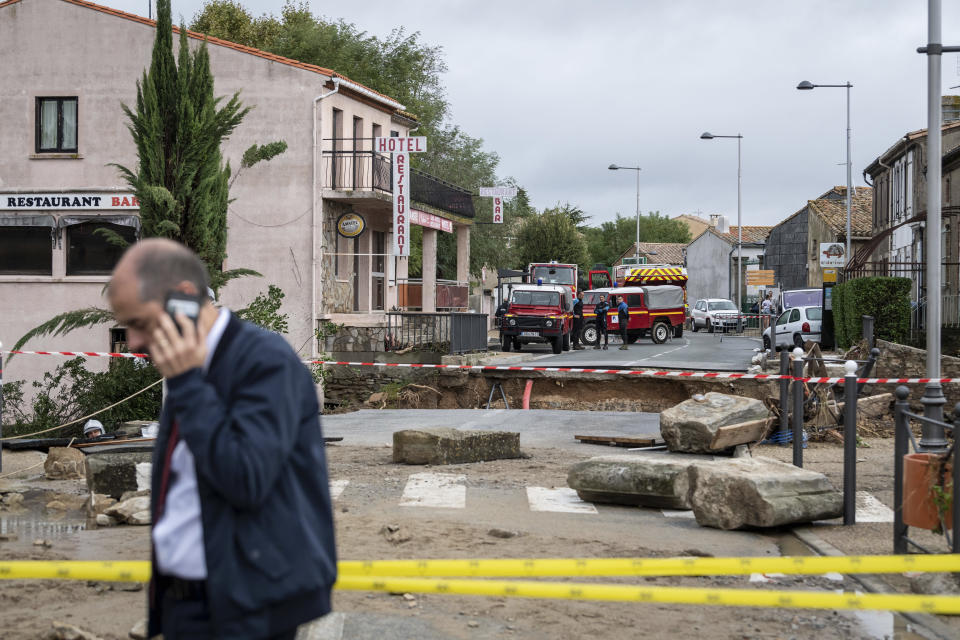 Rescue workers, background, secure the area by a collapsed bridge in the town of Villegailhenc, southern France, Monday, Oct.15, 2018. Flash floods tore through towns in southwest France, turning streams into raging torrents that authorities said killed several people and seriously injured at least five others. (AP Photo/Fred Lancelot)
