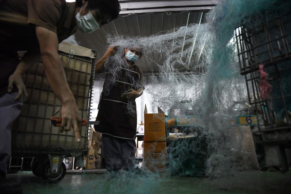 <p>Dos empleados trabajan con las redes que posteriormente se convertirán en otros productos. (Foto: Lillian Suwanrumpha / AFP / Getty Images).</p> 