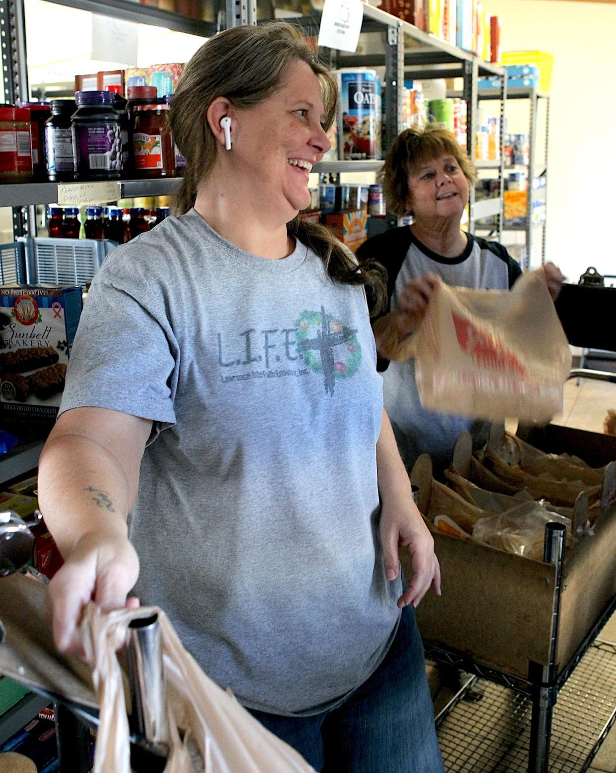 Lawrence County Interfaith Endeavor (LIFE) Food Pantry Administrative Assistant Christy Walls smiles as she fills food orders Tuesday, Nov. 12, 2023. LIFE Food Pantry Director of Operations Laura Bailey is in the background.