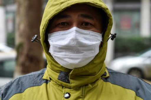 A man working as a volunteer delivering medicine waits outside a pharmacy in Wuhan