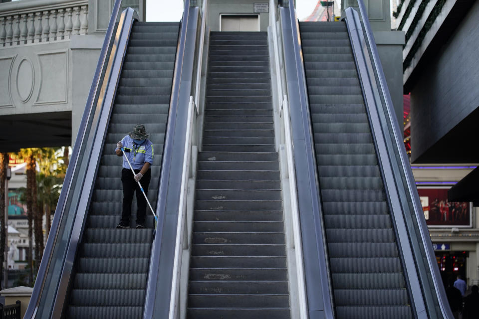 A worker cleans an escalator along the Las Vegas Strip, Thursday, Nov. 19, 2020, in Las Vegas. As the coronavirus surges to record levels in Nevada, the governor has implored residents to stay home. But Democrat Steve Sisolak has also encouraged out-of-state visitors, the lifeblood of Nevada's limping economy, to come to his state and spend money in Las Vegas. (AP Photo/John Locher)