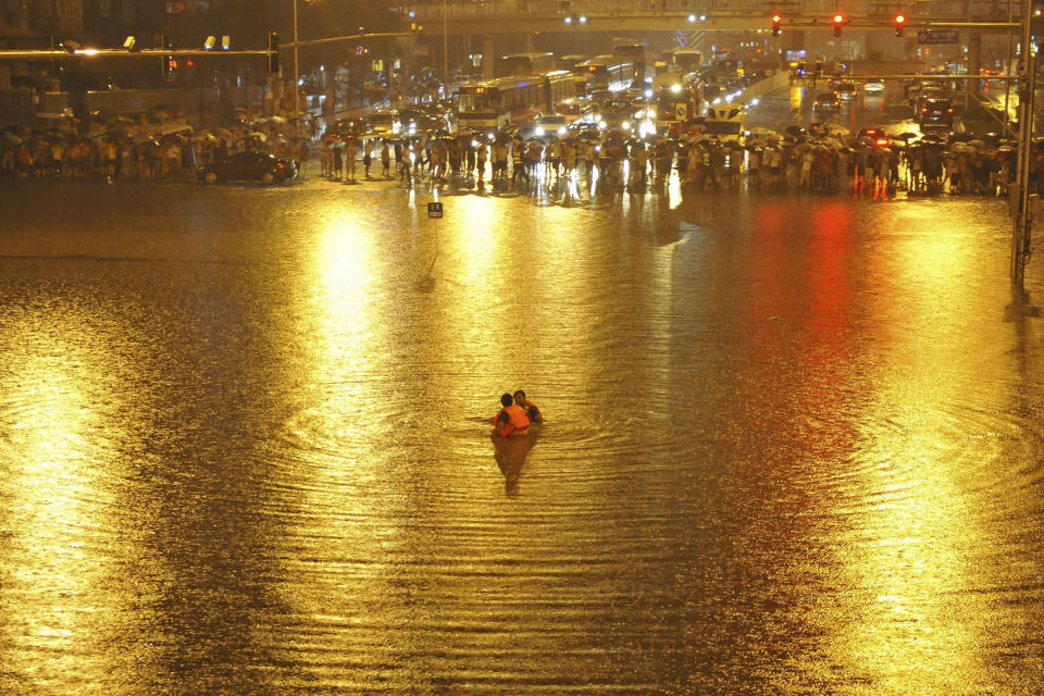 In this Saturday, July 21, 2012 photo, people watch as rescuers search for victims near a flooded underpass after heavy rains in Beijing. Residents impatient for official updates compiled their own death tolls Thursday, July 26, 2012, for last weekend's massive flooding in Beijing and snapped up survival gear following new forecasts of rain, reflecting deep mistrust of the government's handling of the disaster. (AP Photo) CHINA OUT