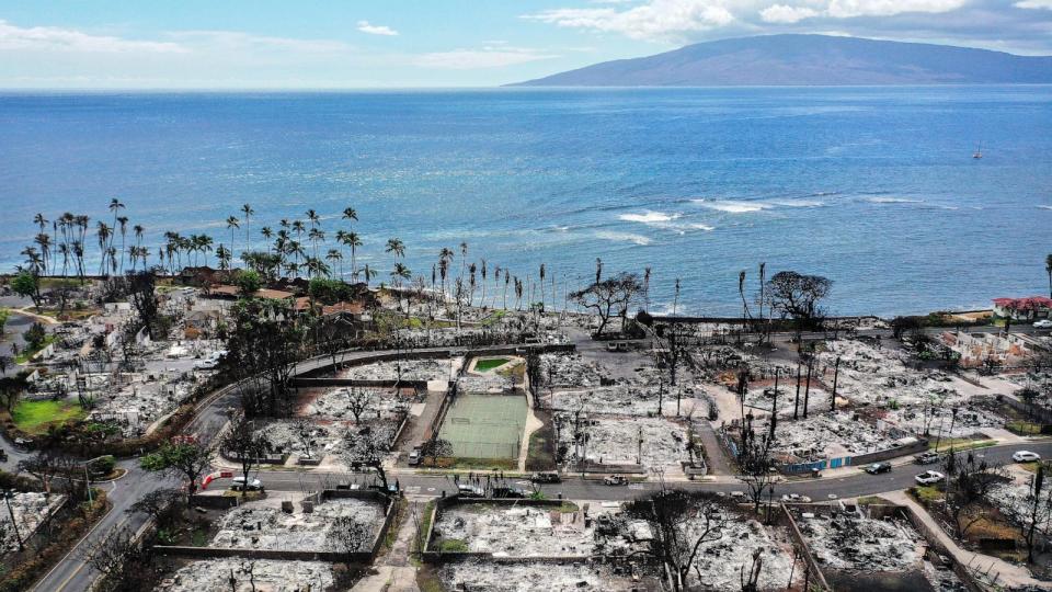 PHOTO: In an aerial view, a recovery vehicle drives past burned structures and cars two months after a devastating wildfire, Oct. 9, 2023, in Lahaina, Hawaii.  (Mario Tama/Getty Images)