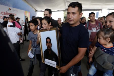 Relatives of a police officer, who was killed along other fellow police officers during an ambush by suspected cartel hitmen, carry his framed photo during an homage organised by the state government, in Morelia