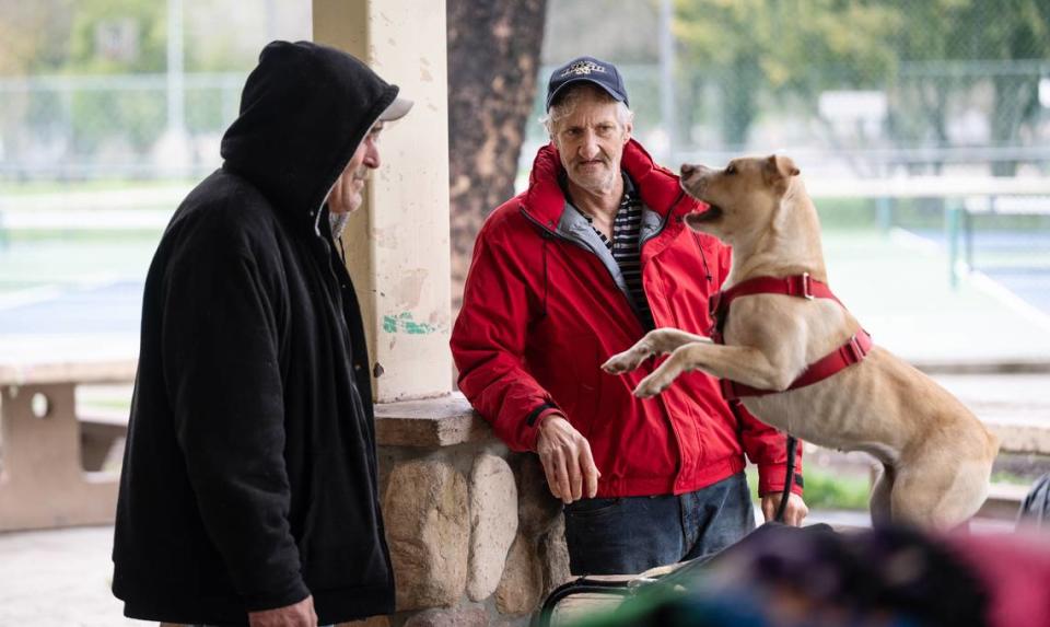 Homeless residents Gary McNeil, right, and Kevin Walker, left, with Walker’s dog Ally at Graceada Park in Modesto on March 29, 2023.