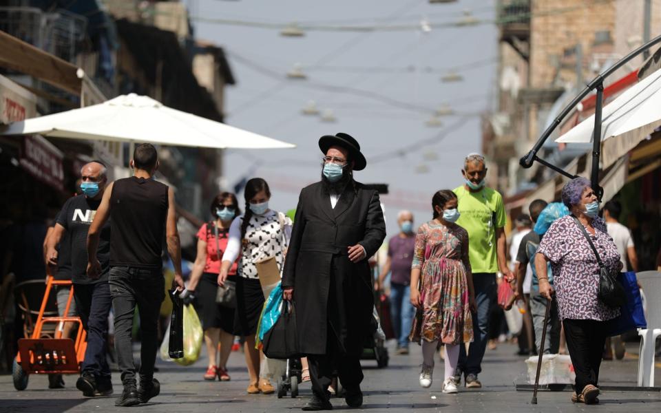 People wearing protective face masks shop at the Mahane Yehuda market ahead of the Rosh Hashana holiday lockdown in Jerusalem - Shutterstock