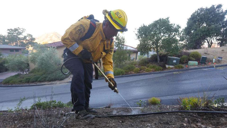 Chad Allison, a firefighter with Cal Fire Shell Beach, extinguishes a hot spot on Lizzie Street, the morning after the quick-moving Lizzie Fire scorched 100 acres in the hills above San Luis Obispo High School on Oct. 30, 2023.