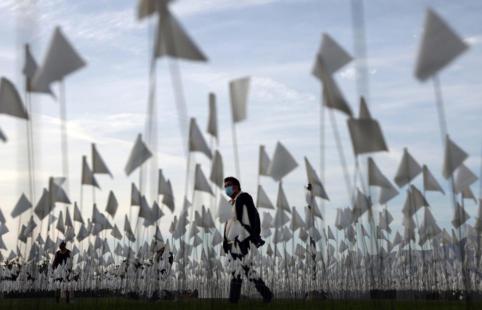 A person wearing a face covering walks past a white flag memorial installation outside Griffith Observatory honoring the nearly 27,000 Los Angeles County residents who have died from COVID-19 on November 18, 2021 in Los Angeles, California. Los Angeles is holding a three-day citywide ‘Strength and Love’ memorial honoring those who died and those who ‘have held the city together throughout the pandemic’ including first responders and essential workers. Los Angeles County reported 26 additional deaths due to COVID-19 today. 