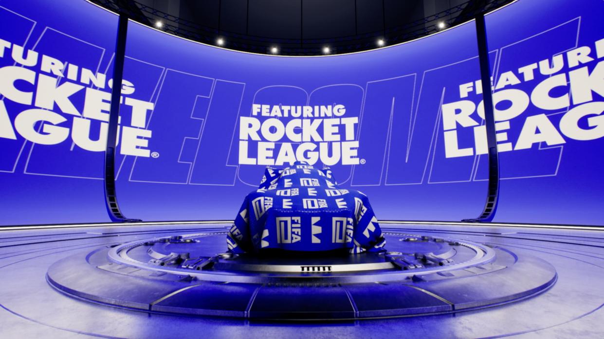  An image of a Rocket League car underneath a FIFA-branded shround on a virtual stage. The text "Featuring Rocket League" is prominently displayed on a screen behind it. 