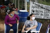 Esther Dominguez, left, and Liz Cristaldo sit outside the ICU of the Respiratory Hospital INERAM where their relatives are being treated for COVID-19 in Asuncion, Paraguay, Wednesday, March 3, 2021, the day after INERAM Director Felipe Gonzalez resigned. Without vaccines or basic drugs to combat COVID-19, Paraguay's main public hospitals became unable to receive patients in intensive care units on Wednesday. (AP Photo/Jorge Saenz)