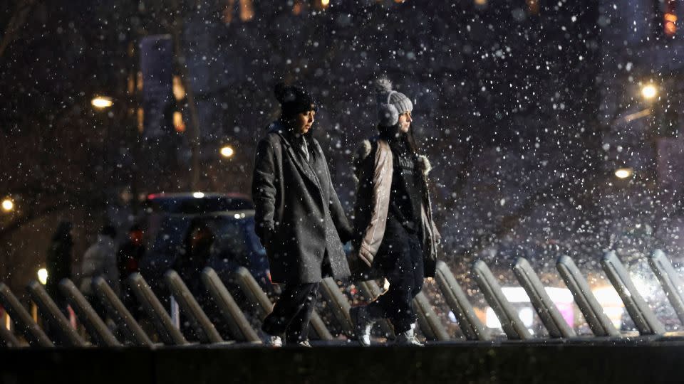 People walk as snow falls in New York City on Saturday. - Andrew Kelly/Reuters