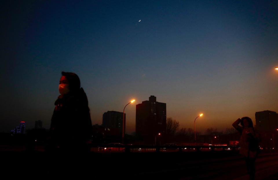 A star is twinkling above a pedestrian wearing a mask silhouetted against the city skyline shrouded in heavy smog in Beijing Monday, Jan. 2, 2017. Beijing and other cities across northern and central China were shrouded in thick smog Monday, Jan. 2, 2017, prompting authorities to delay dozens of flights and close highways. (AP Photo/Andy Wong)