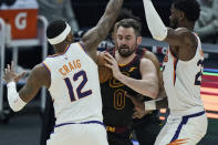 Cleveland Cavaliers Kevin Love, center, tries to get past Phoenix Suns' Torrey Craig, left, and Deandre Ayton, right, in the first half of an NBA basketball game, Tuesday, May 4, 2021, in Cleveland. (AP Photo/Tony Dejak)