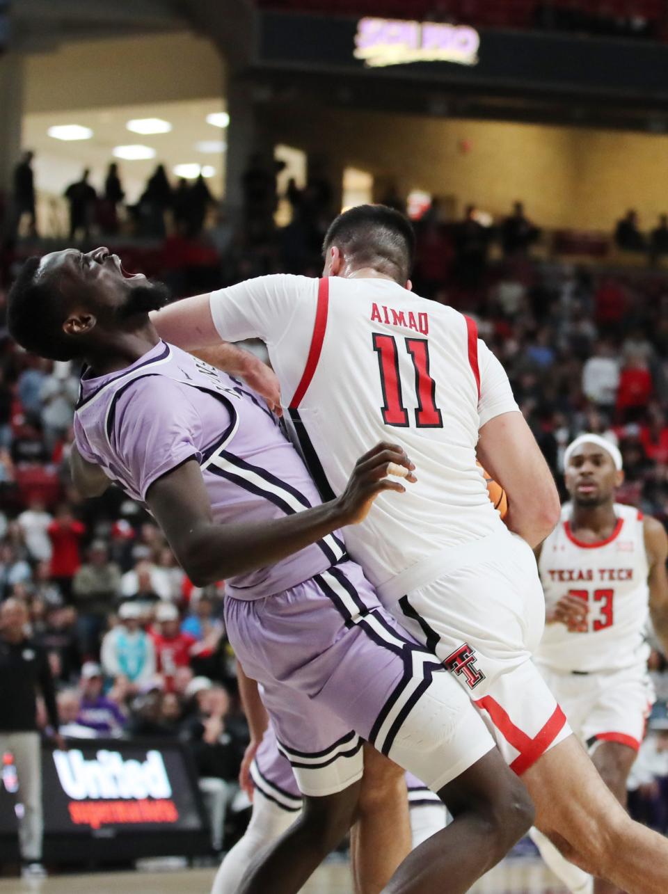 Kansas State center Abayomi Iyiola (23) draws a charging foul against Texas Tech's Fardaws Aimaq (11) during Saturday's game at United Supermarkets Arena in Lubbock, Texas.