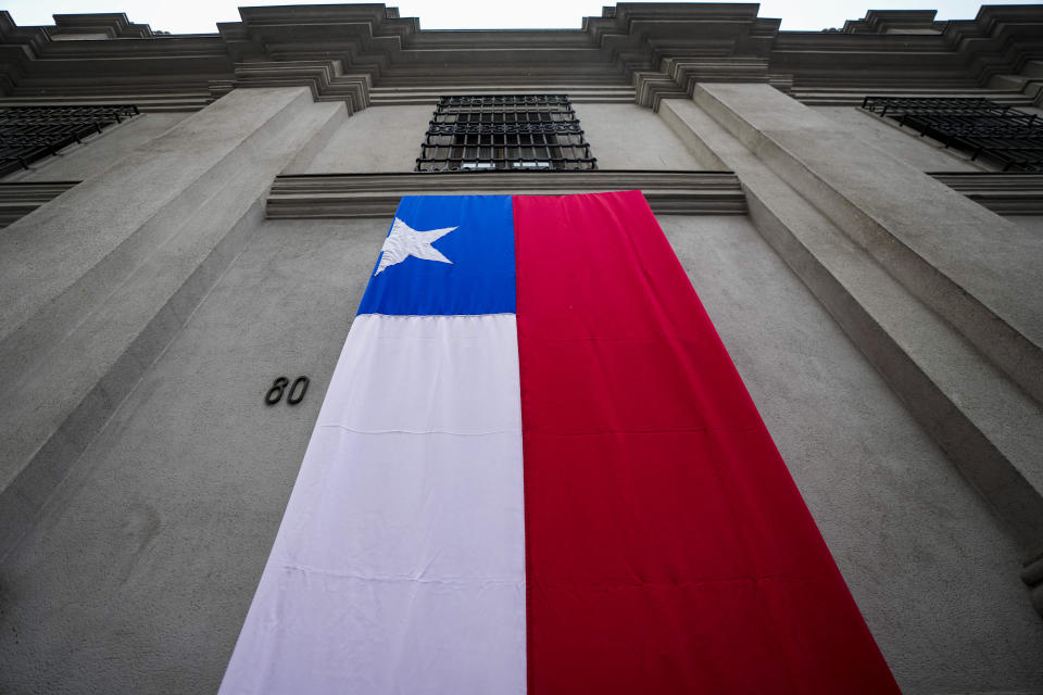 The eastern entrance of La Moneda presidential palace is draped with a Chilean flag during an event marking late Salvador Allende's 1970 presidential victory in Santiago, Chile, Monday, Sept. 4, 2023. Allende was ousted from office 50 years ago in a military coup and Chile was governed by a military junta that did not return power to the civilian government until 1990. (AP Photo/Esteban Felix)