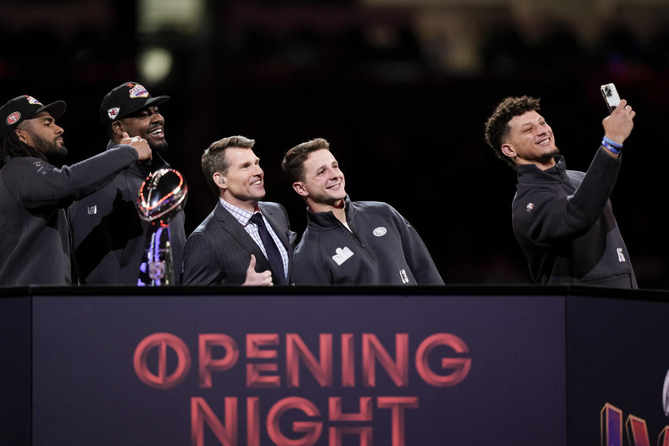 Kansas City Chiefs quarterback Patrick Mahomes (15) takes a photograph with San Francisco 49ers quarterback Brock Purdy (13), NFL Network's Scott Hanson, center, Kansas City Chiefs' Chris Jones (95) and San Francisco 49ers' Fred Warner, left, during the NFL football Super Bowl 58 opening night Monday, Feb. 5, 2024, in Las Vegas. The San Francisco 49ers will play the Kansas City Chiefs in Super Bowl 58 Sunday. (AP Photo/Charlie Riedel)