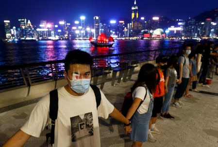 Protesters hold hands to form a human chain during a rally to call for political reforms at the Avenue of Stars in Hong Kong