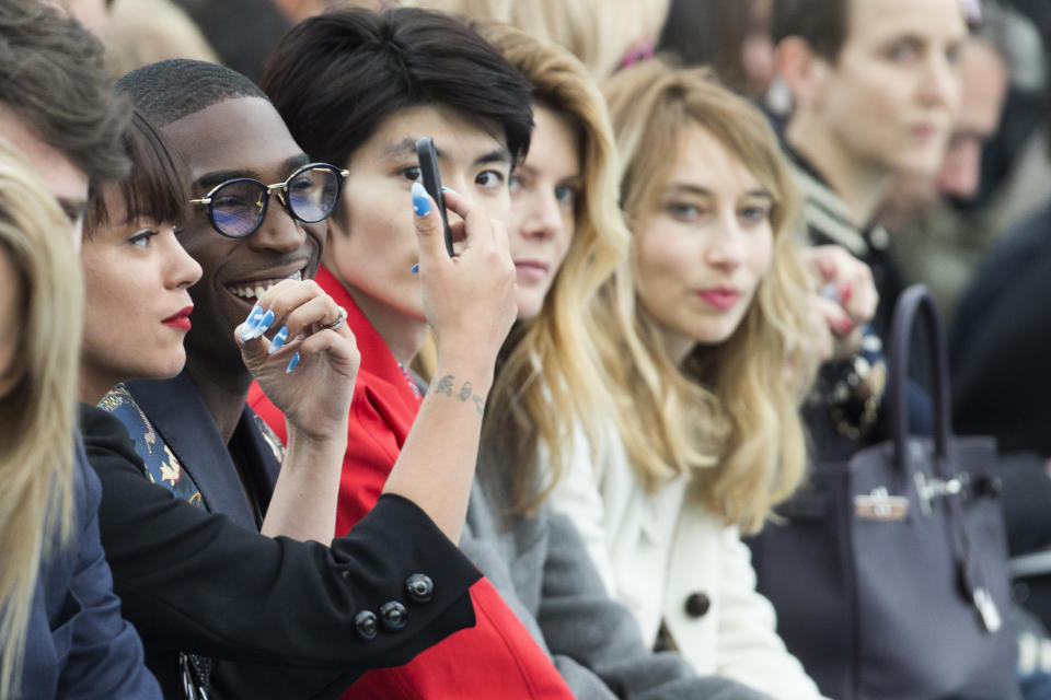 Singer Lily Allen, left, adjusts her make up and she sits next to singer Tinie Tempah, second from left, as they watch the Louis Vuitton men's Fall-Winter 2014-2015 fashion collection, presented Thursday, Jan. 16, 2014 in Paris. (AP Photo/Jacques Brinon)