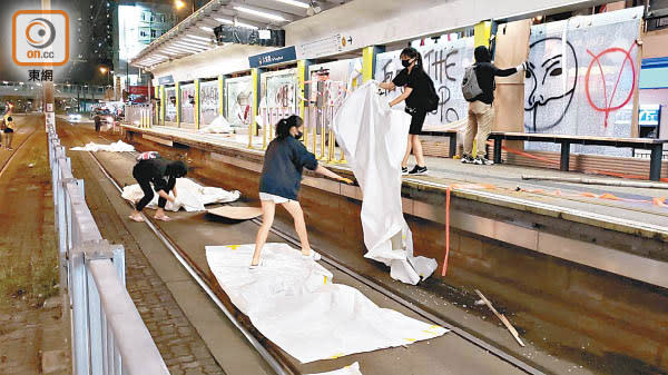 大棠路站<br>暴徒將遮掩玻璃燈箱的大型膠布掉進輕鐵路軌。（朱先儒攝）