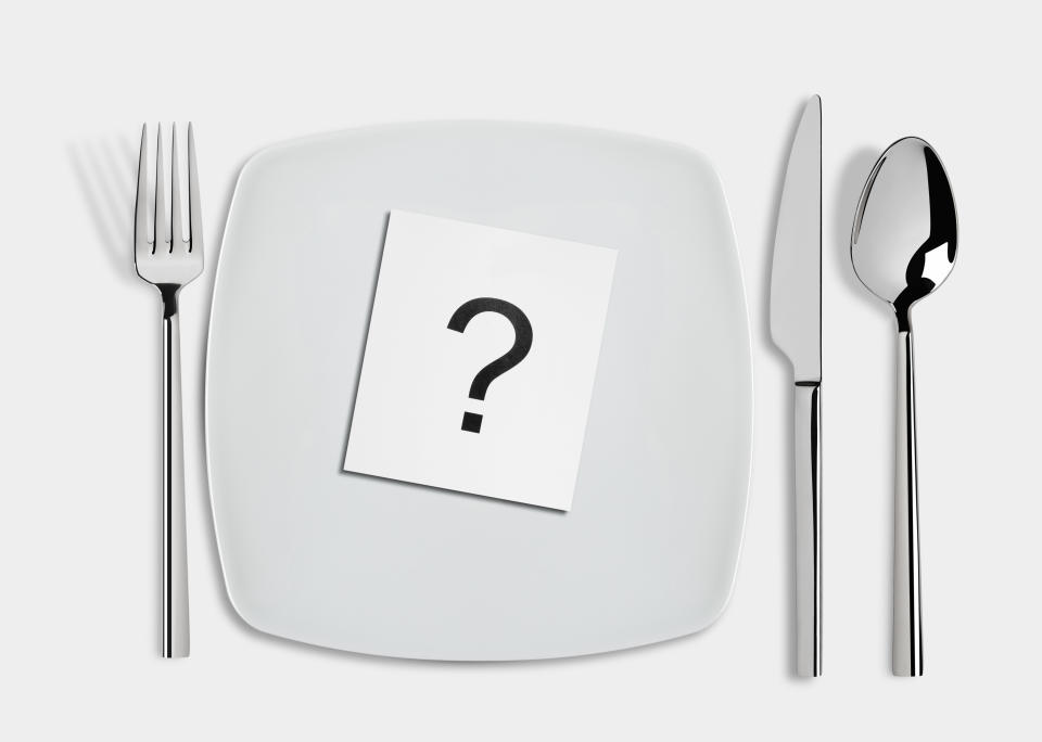 Question mark in  white square plate and fork,spoon and table knife isolated on white background. Conceptual image.