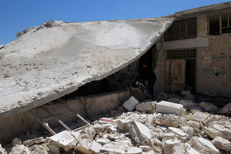 Men salvage a motorbike amid the damage from inside a medical point at a site hit by airstrikes on Tuesday, in the town of Khan Sheikhoun in rebel-held Idlib, Syria April 5, 2017. REUTERS/Ammar Abdullah