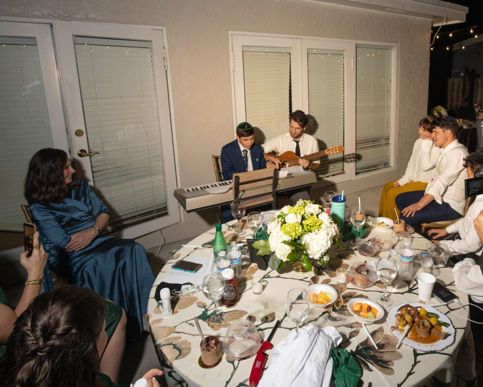 Judy (left) and Menachem (holding the guitar next to his nephew) pictured together at his brother’s wedding (@eighteenpctgrey/Instagram)