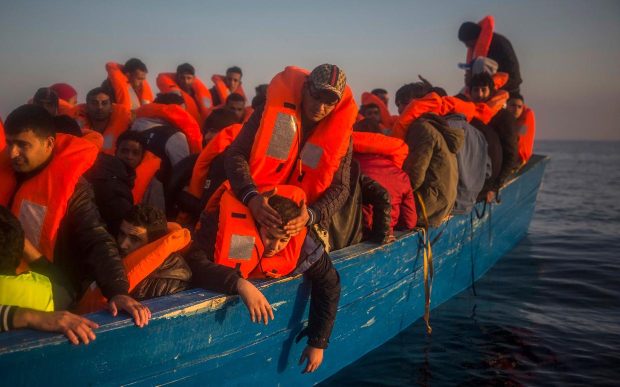 Refugees and migrants crowd onboard a wooden boat, as they wait to be assisted by an NGO off the coast of Libya - Copyright 2017 The Associated Press. All rights reserved.