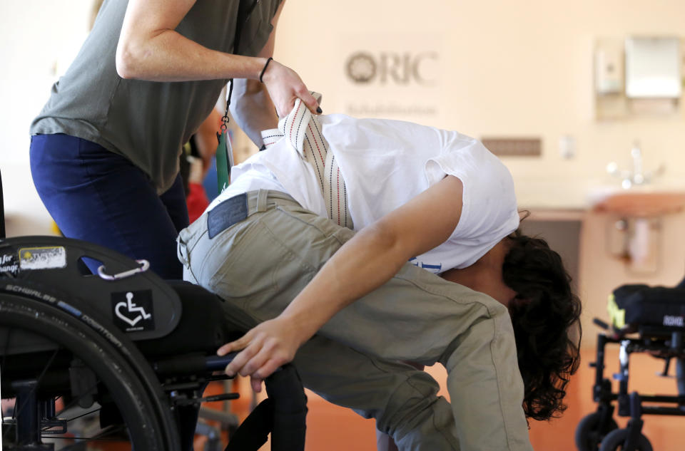FILE - Jonathan Annicks works on a technique in getting back into his wheelchair with the help from physical therapist Kat Lowery in Chicago on Oct. 8, 2016. Six years later Annicks has received a bachelor's degree in communications and media and has become a part-time peer advisor for patients at the same rehabilitation hospital where he was a patient. (AP Photo/Charles Rex Arbogast File)