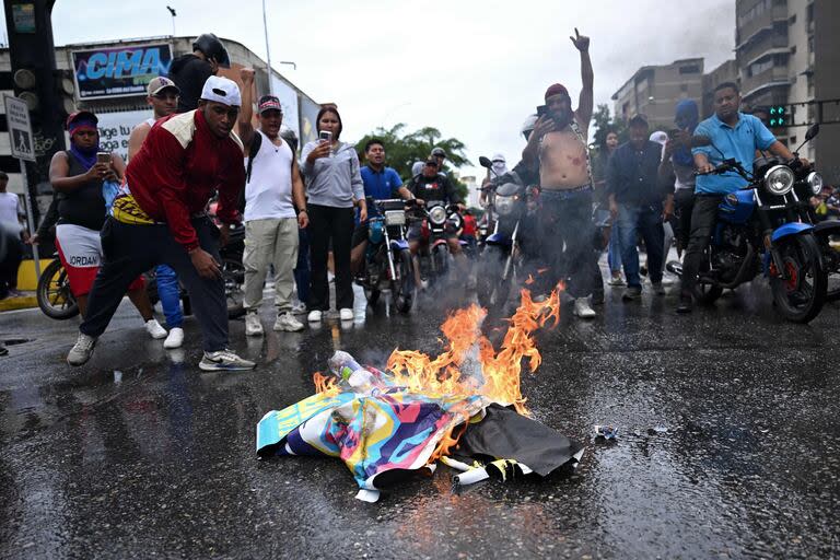 Opositores al gobierno del presidente venezolano Nicolás Maduro queman carteles de campaña de Maduro durante una protesta en el barrio de Petare en Caracas
