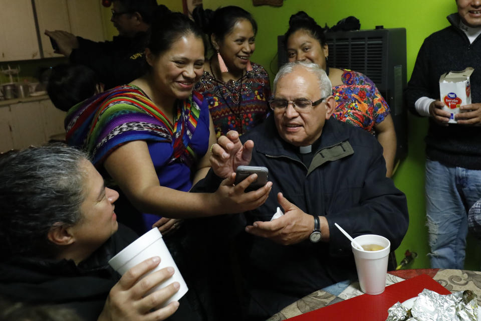 FILE - Cristel Cordona, second from left, shows photos of a recent marriage to visiting Guatemalan Cardinal Alvaro Ramazzini, at the St. Anne Catholic Church, in Carthage, Miss., Dec. 20, 2019. Ramazzini was at the parish to participate in a listening session with immigrants impacted by arrests by immigration agents at seven Mississippi food processing plants. (AP Photo/Rogelio V. Solis, File)