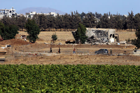 Uniformed men walk in Quneitra on the Syrian side of the ceasefire line between Israel and Syria, as seen from the Israeli-occupied Golan Heights, July 26, 2018. REUTERS/Ammar Awad