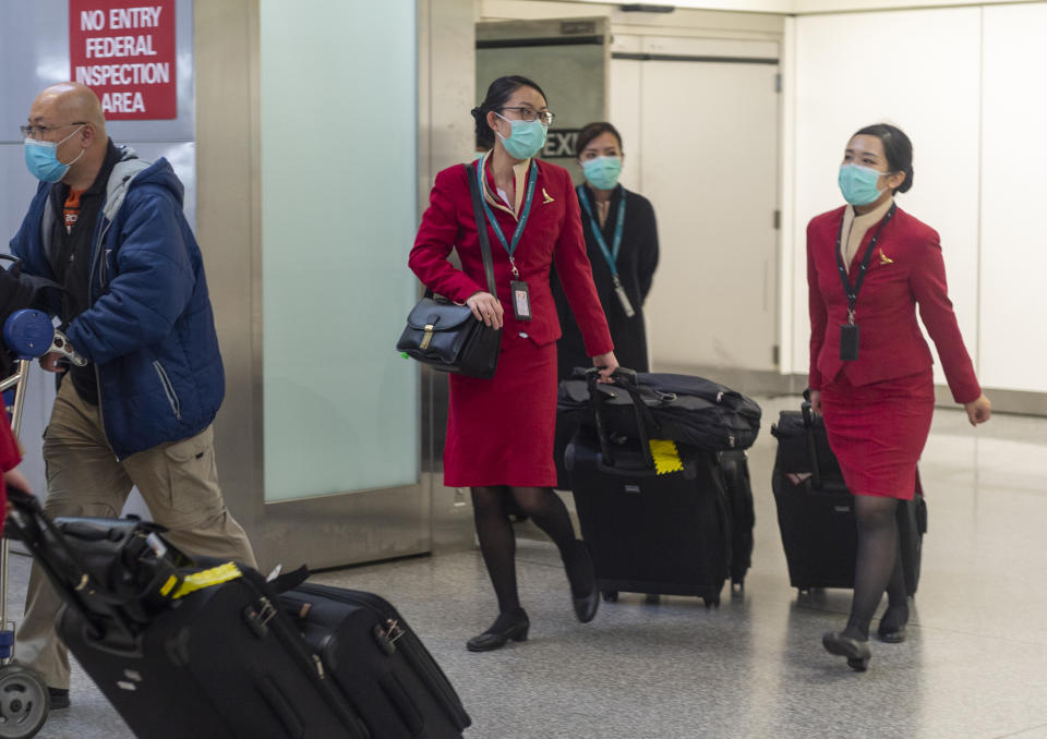 Cathay Pacific Airways cabin crew wearing face masks walk out of the international terminal at the San Francisco International Airport in Millbrae, California, United States on January 28, 2020. There are now 8,235 confirmed cases of coronavirus, with 171 death and 143 recovered. (Photo by Yichuan Cao/NurPhoto via Getty Images)