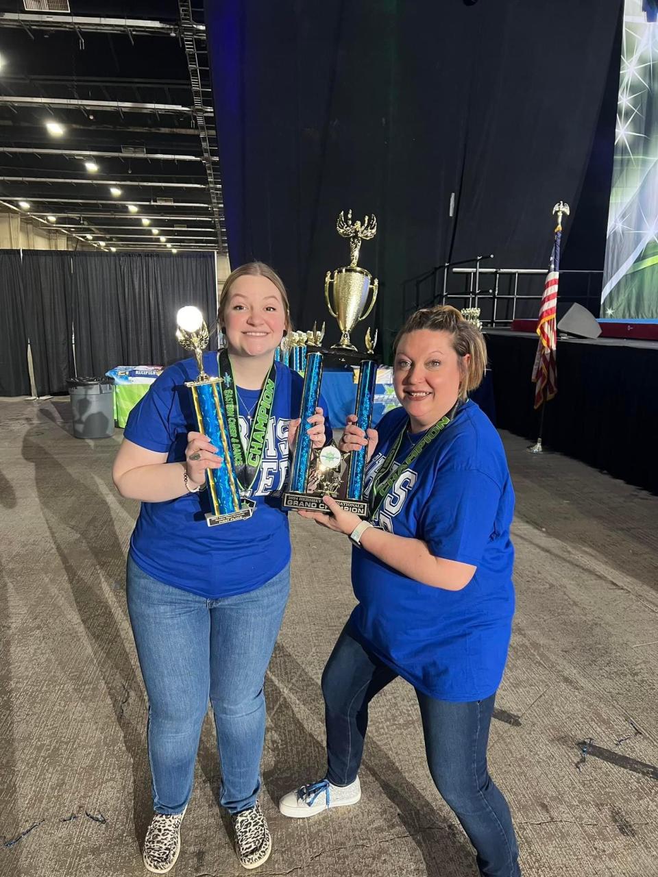 Assistant coach Gabby O'Malley (left) and head coach Megan Hazelton pose with Narragansett's hardware after winning at the Eastern National High School Cheerleading Championships.