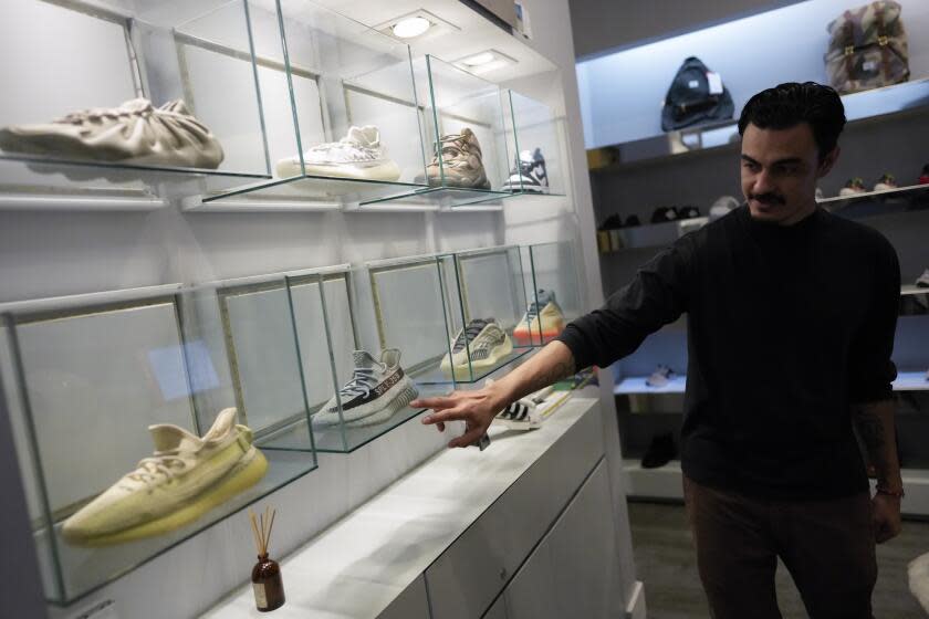 A store manager points out Yeezy shoes made by Adidas that are displayed inside cases at Addict shoe store in Brickell City Center in Miami, Tuesday, Oct. 25, 2022. (AP Photo/Rebecca Blackwell).