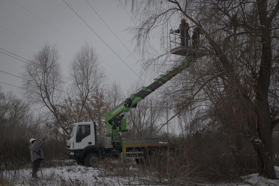 Workers of the electricity supply company DTEK maintain power lines by cutting off excess branches in Kyiv, Ukraine, Thursday, Dec. 8, 2022. Ukrainian utility crews struggling to patch up power lines during a two-month Russian military blitz targeting Ukrainian infrastructure are learning to adapt. And just as on the battlefield, Ukrainians are learning to respond quickly on the new energy front drawn inside homes, hospitals, offices, and schools in yet another act of defiance against a powerful invader. (AP Photo/Andrew Kravchenko)