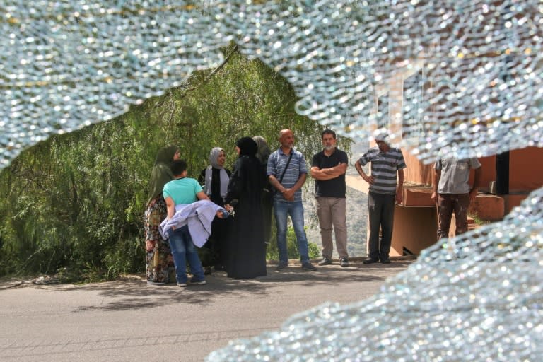 Onlookers are seen through the smashed windshield of the school bus that was damaged in the strike (Mahmoud ZAYYAT)