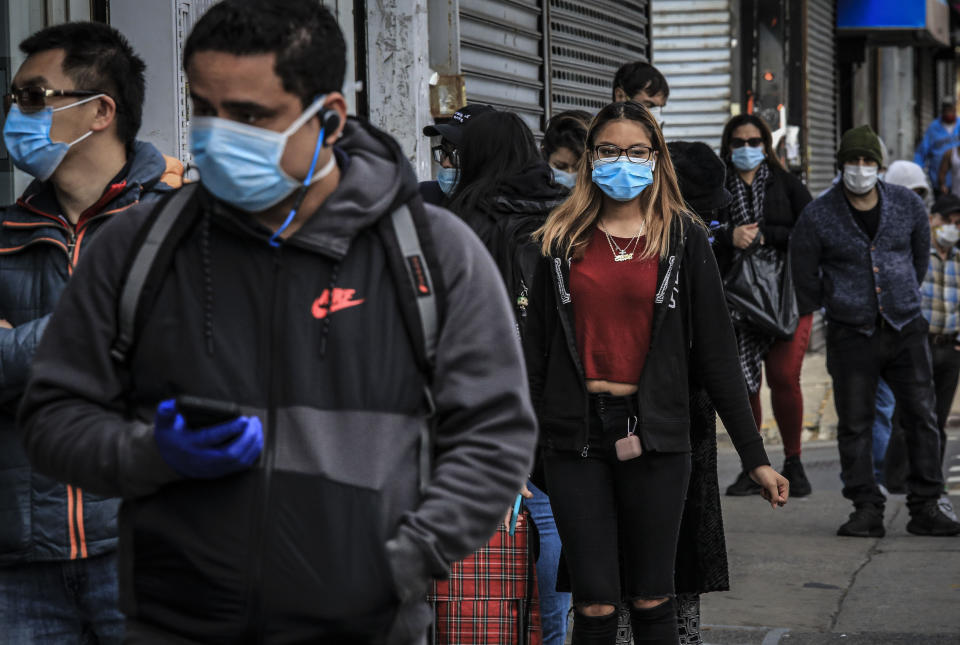 People in Brooklyn's Sunset Park, a neighborhood with one of the city's largest Mexican and Hispanic community, wear masks to help stop the spread of coronavirus while waiting in line to enter a store, Tuesday May 5, 2020, in New York. A poll found that 61% of Hispanic Americans say they've experienced some kind of household income loss as a result of the COVID-19 outbreak. (AP Photo/Bebeto Matthews)